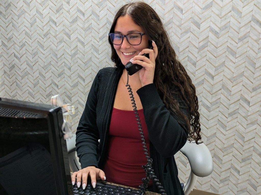 A member of the front desk team smiling as she answers the phone